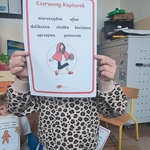 Dziewczynka trzyma kartkę z cechami 