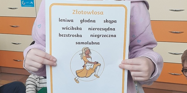Dziewczynka trzyma kartkę z wypisanymi cechami tytułowej bohaterki "Złotowłosej"