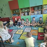 Uczniowie klasy I A słuchają książki, którą czyta bibliotekarka