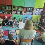 Uczniowie klasy I A słuchają książki, którą czyta bibliotekarka