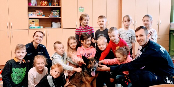 Uczniowie klasy Ia pozują z policjantami i psem do zdjęcia.