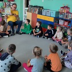 Bibliotekarz prezentuje dzieciom książkę.