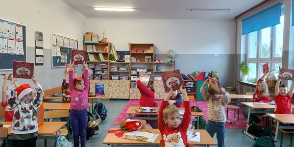 Dzieci prezentują książkę którą otrzymały w prezencie.