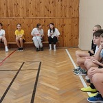Zdjęcie przedstawiające uczniów klasy szóstej czekających na swoje mecze w turnieju badmintona