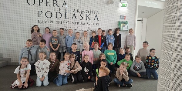 Uczniowie klas III na wspólnym zdjęciu przy logo Opery i Filharmonii Podlaskiej