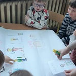 Dzieci siedzące przy ławce w trakcie zajęć